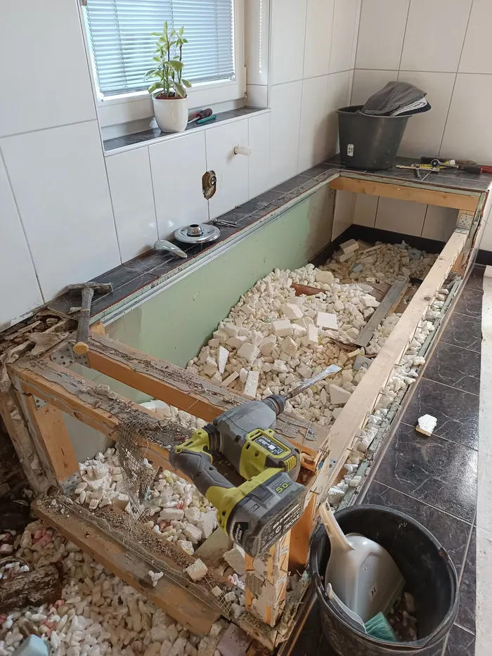 Demolished bathroom wall showing rotten timber frame behind tiles